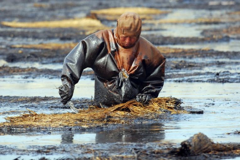 Рабочий устраняет разливы нефти в порту Далянь в Ляонине